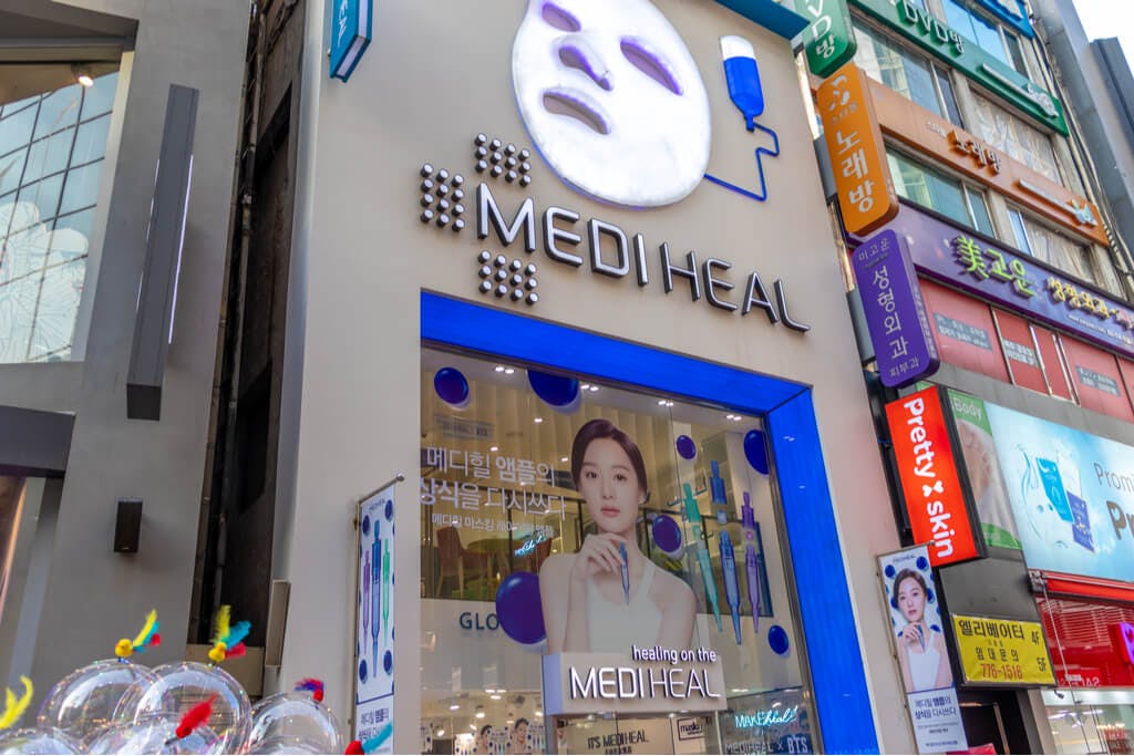 The front of a Mediheal branch in Seoul with a display of a woman with beautiful skin in front