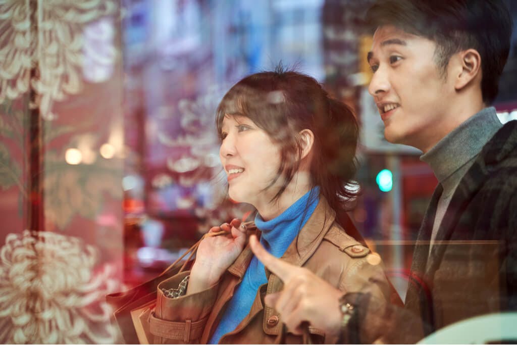 A couple looks in the window of a display at a store around Christmas time.