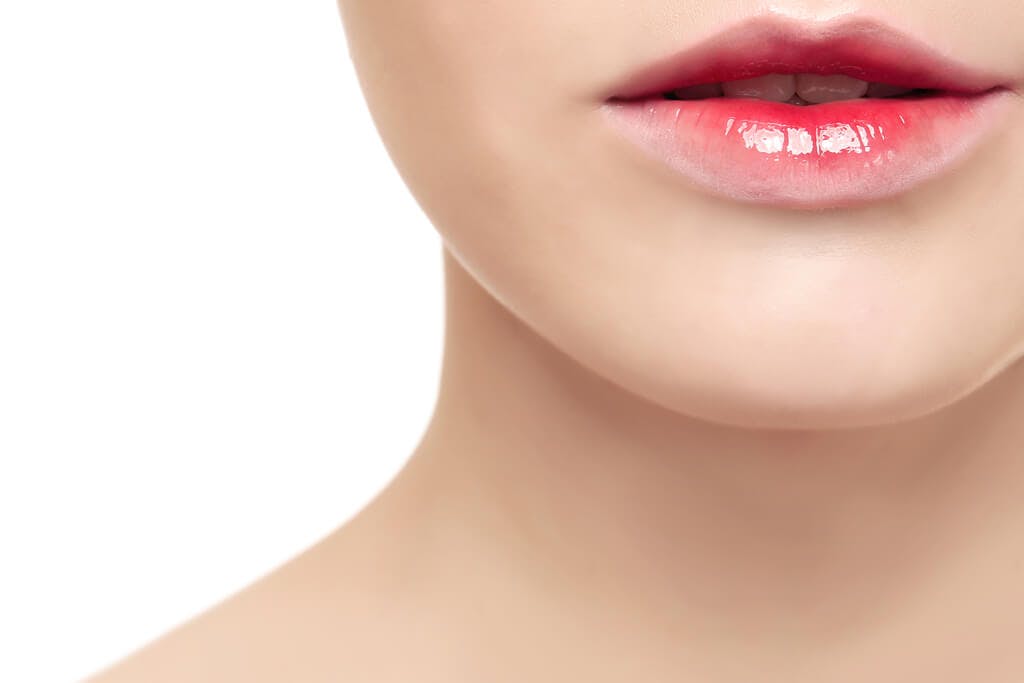 A woman's lip with a lip tint that is gradiated from red in the center