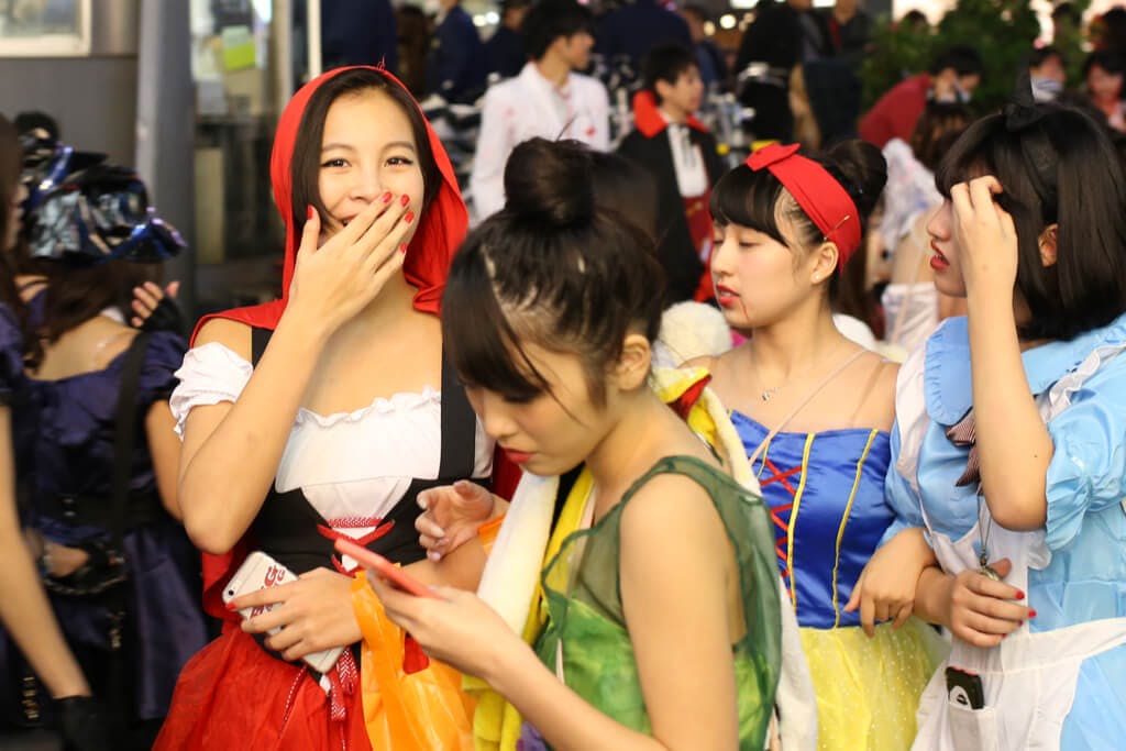 4 women dressed as fairy tale characters at the Shibuya Halloween event with people in costumes behind them