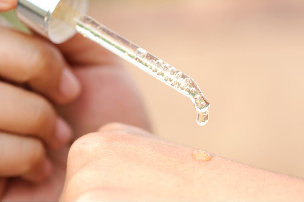 A person uses a Vitamin C drop on the back of their hand