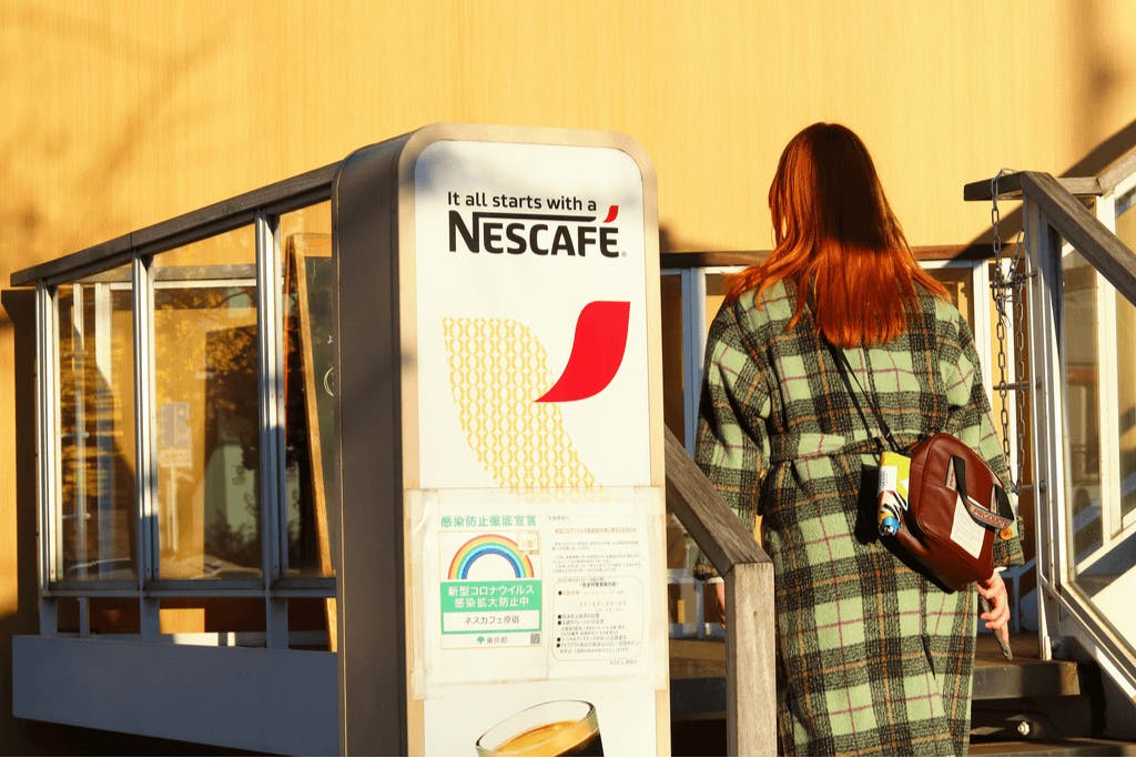 A woman with in a stylish green jacket walks into Nescafe, one of the Harajuku cafes off of Takeshita Street.