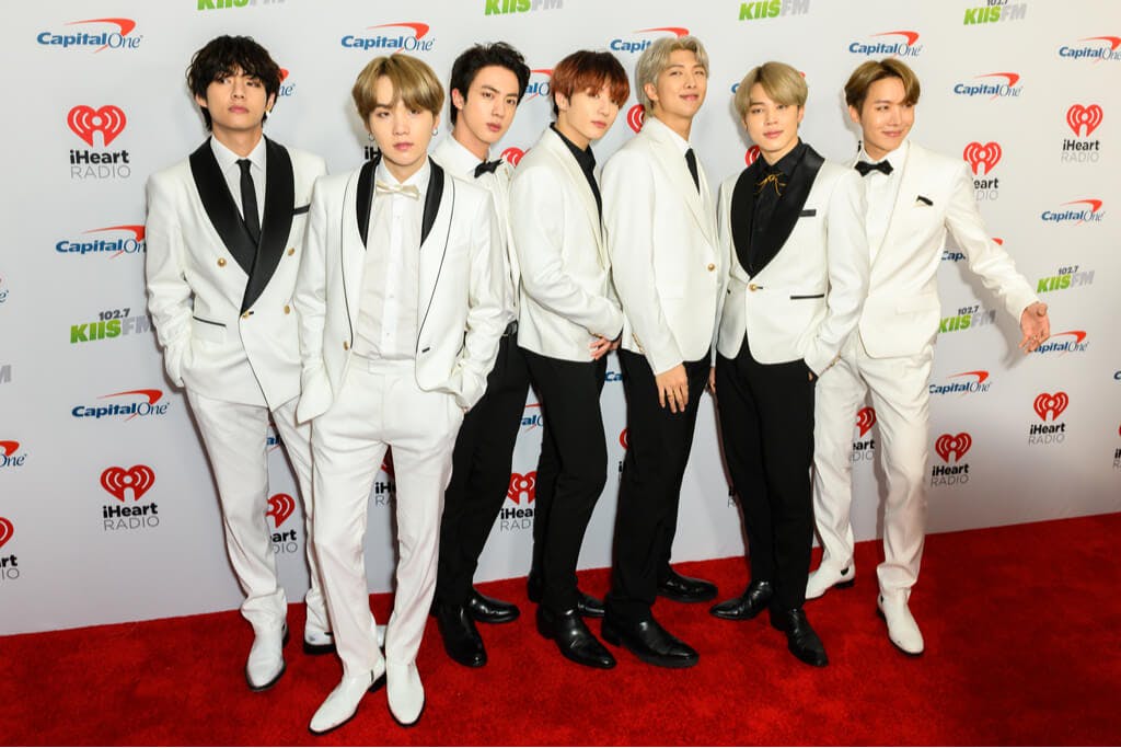 BTS members in white and black suits at a music award show. 