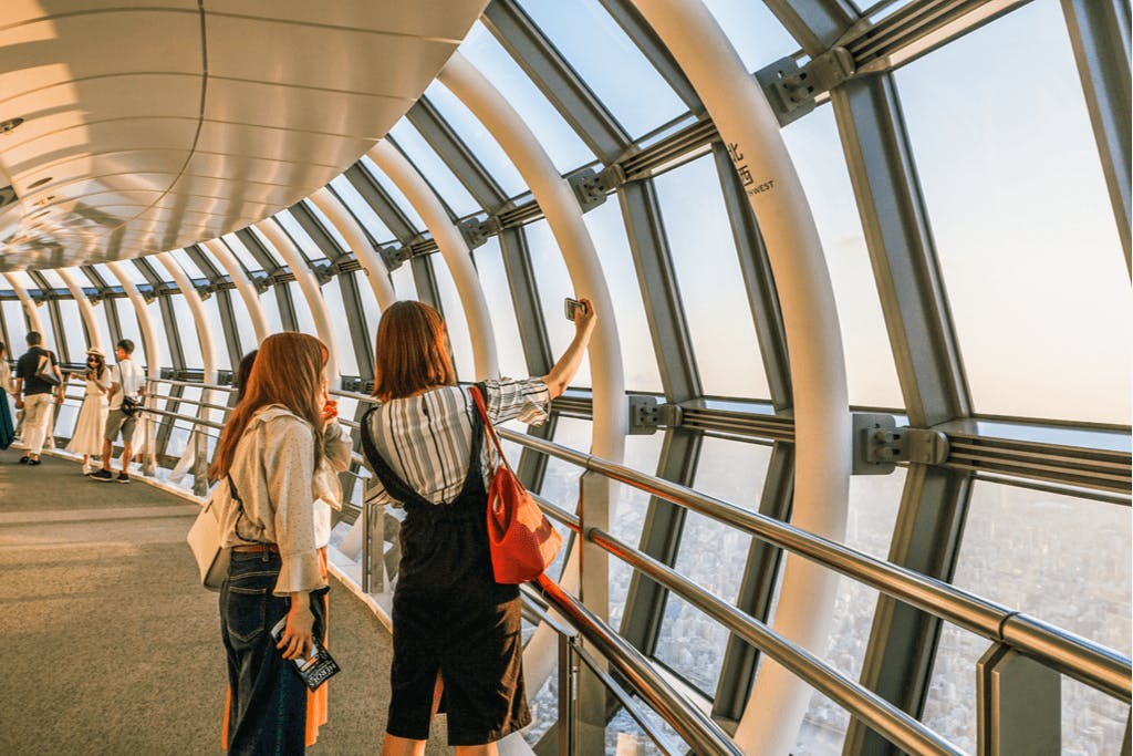 Three women take a photo together while looking out over the view from Tokyo Skytree, a popular date spot in Tokyo.