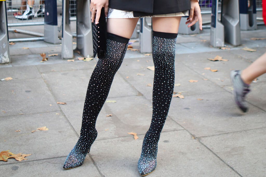 A woman wearing long, black, sparkly boots at fashion event
