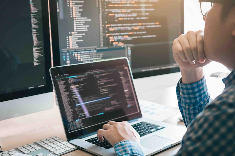 Programmer looking at code on laptop