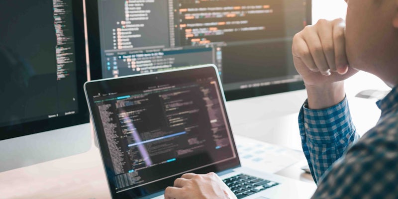 Programmer looking at code on laptop