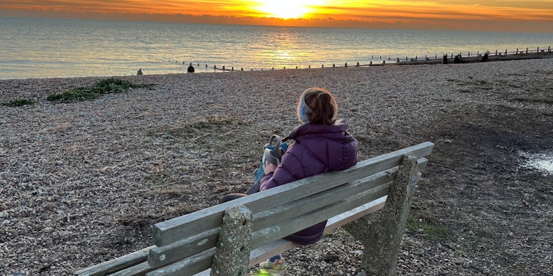 Kate sitting on a bench at the beach