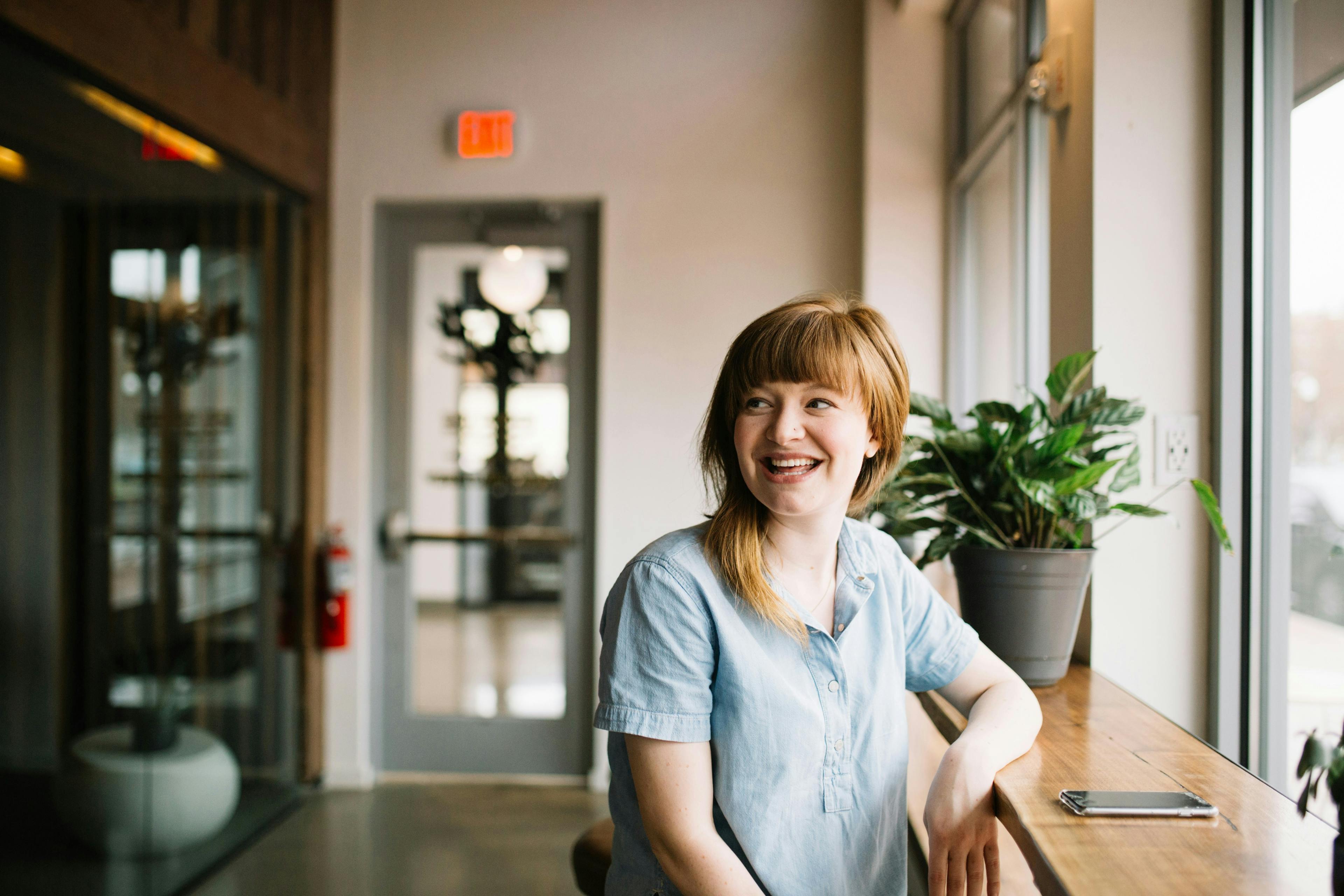 A red-haired young woman sitting at a high counter, credit: brooke-cagle-unsplash