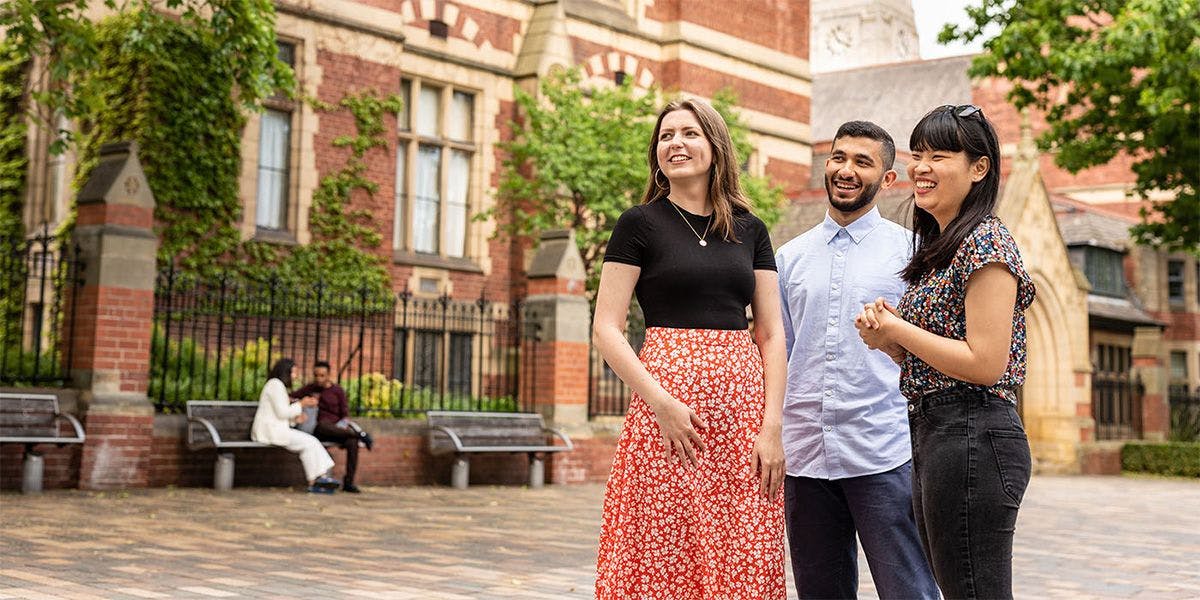 Three students standing outside the University of Leeds