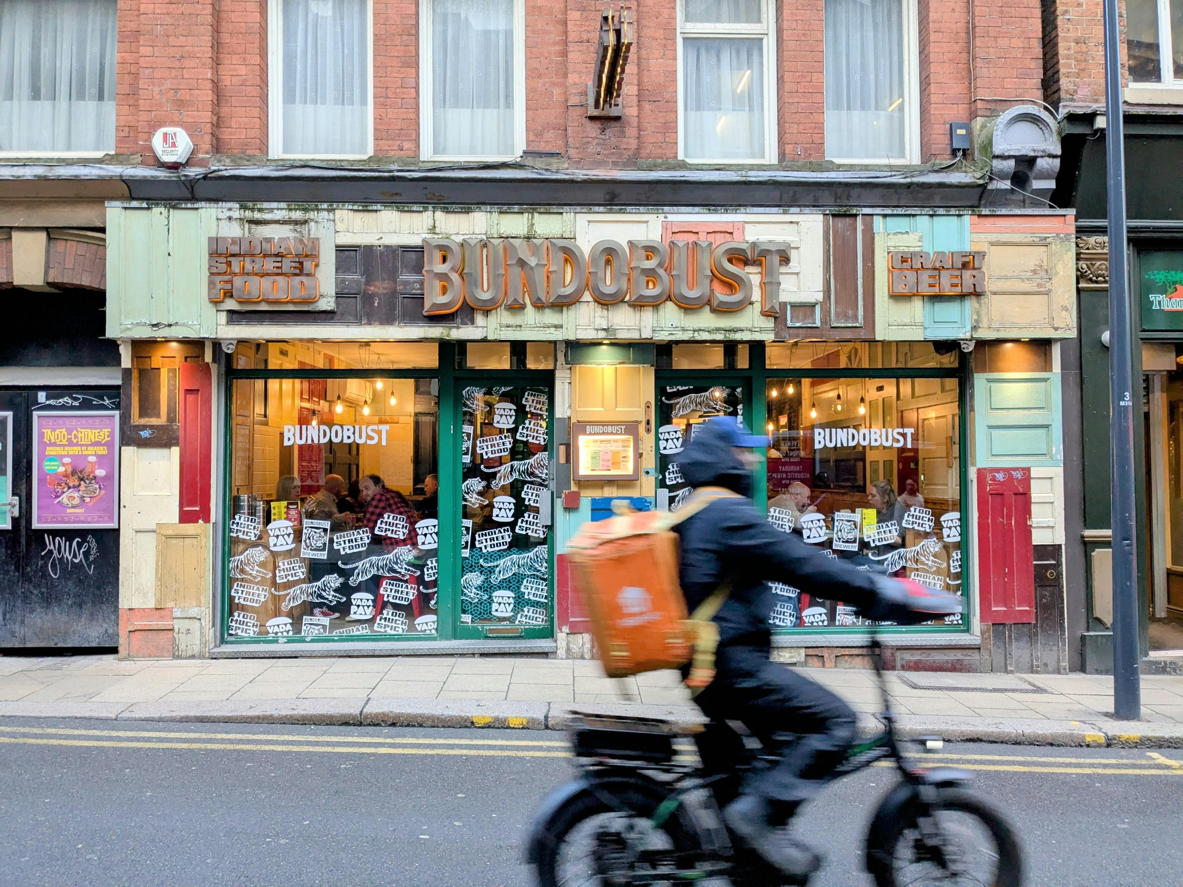 A food delivery person cycling past Bundobust, Leeds.