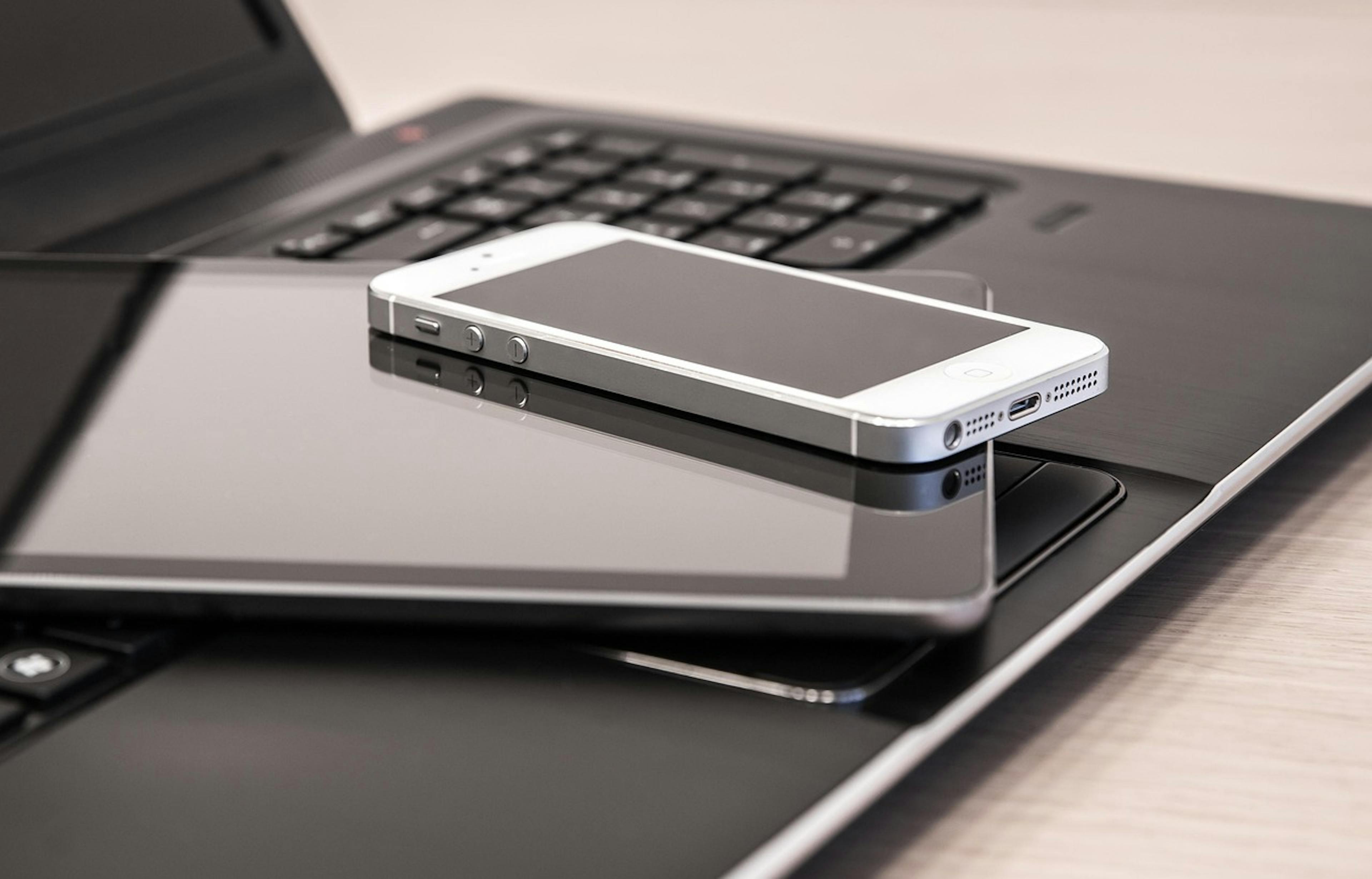 An image of a phone and an iPad on top of a laptop keyboard - it is the main image for the article "Goal Planner: 7 Best Goal Planners To Achieve Your Goals"