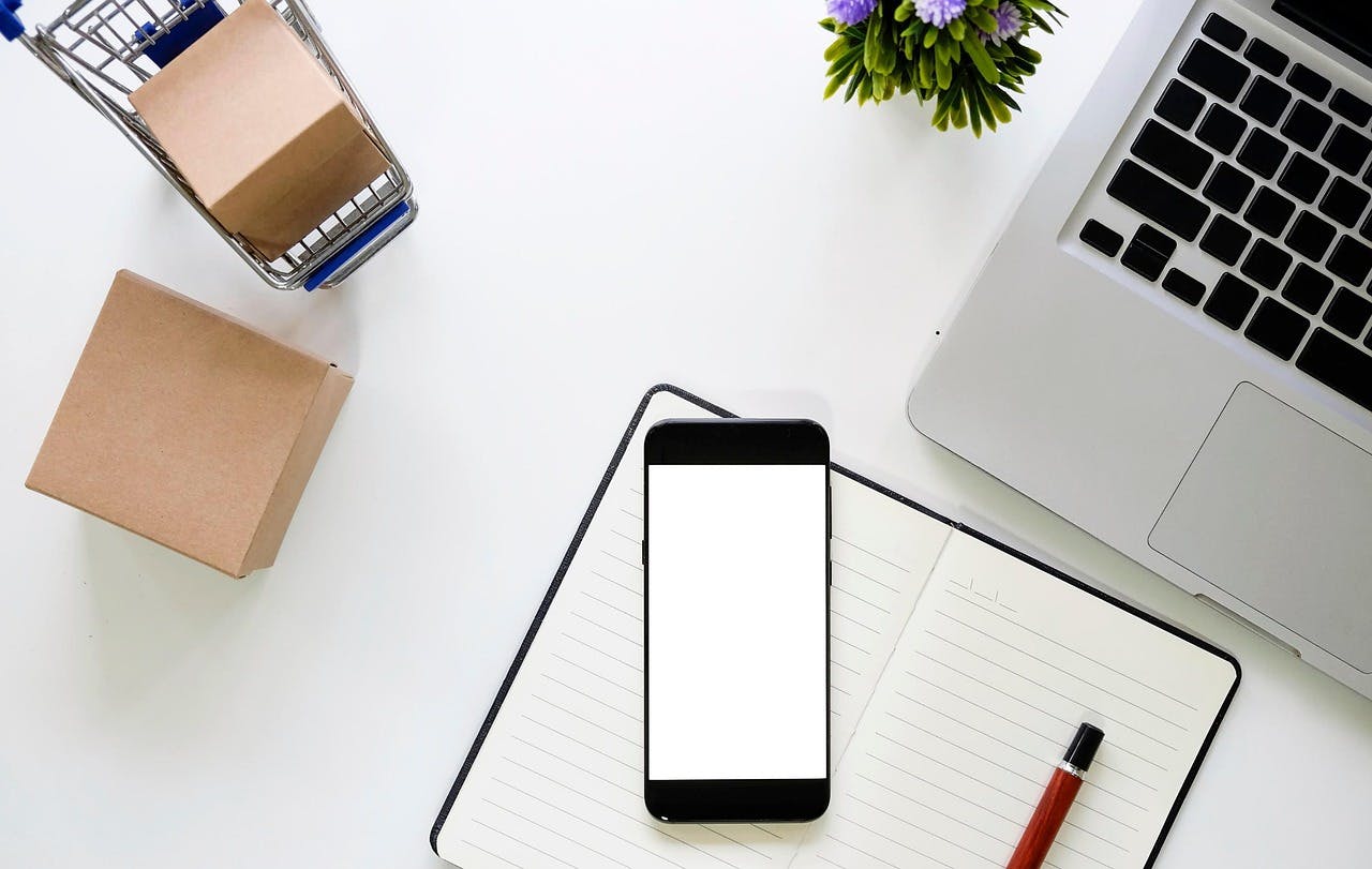 An image of a phone and notebook on a clear table - it is the main image for the article "Online Diary: The Top 5 Online Diaries Of 2025"