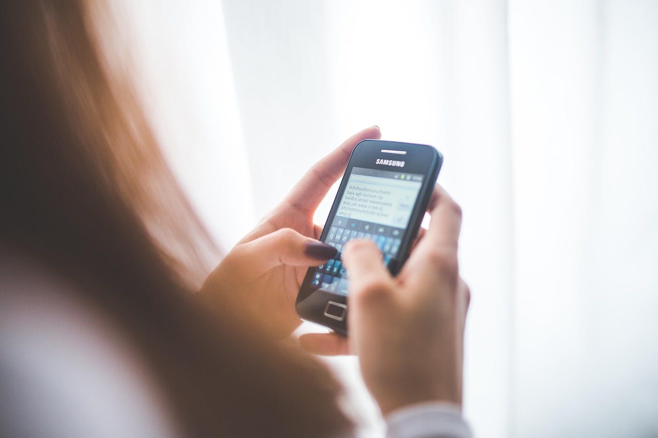 An image of a woman typing on her phone - it is the main image for the article "Journaling Apps: 7 Simple Journals That Make Journaling a Breeze"