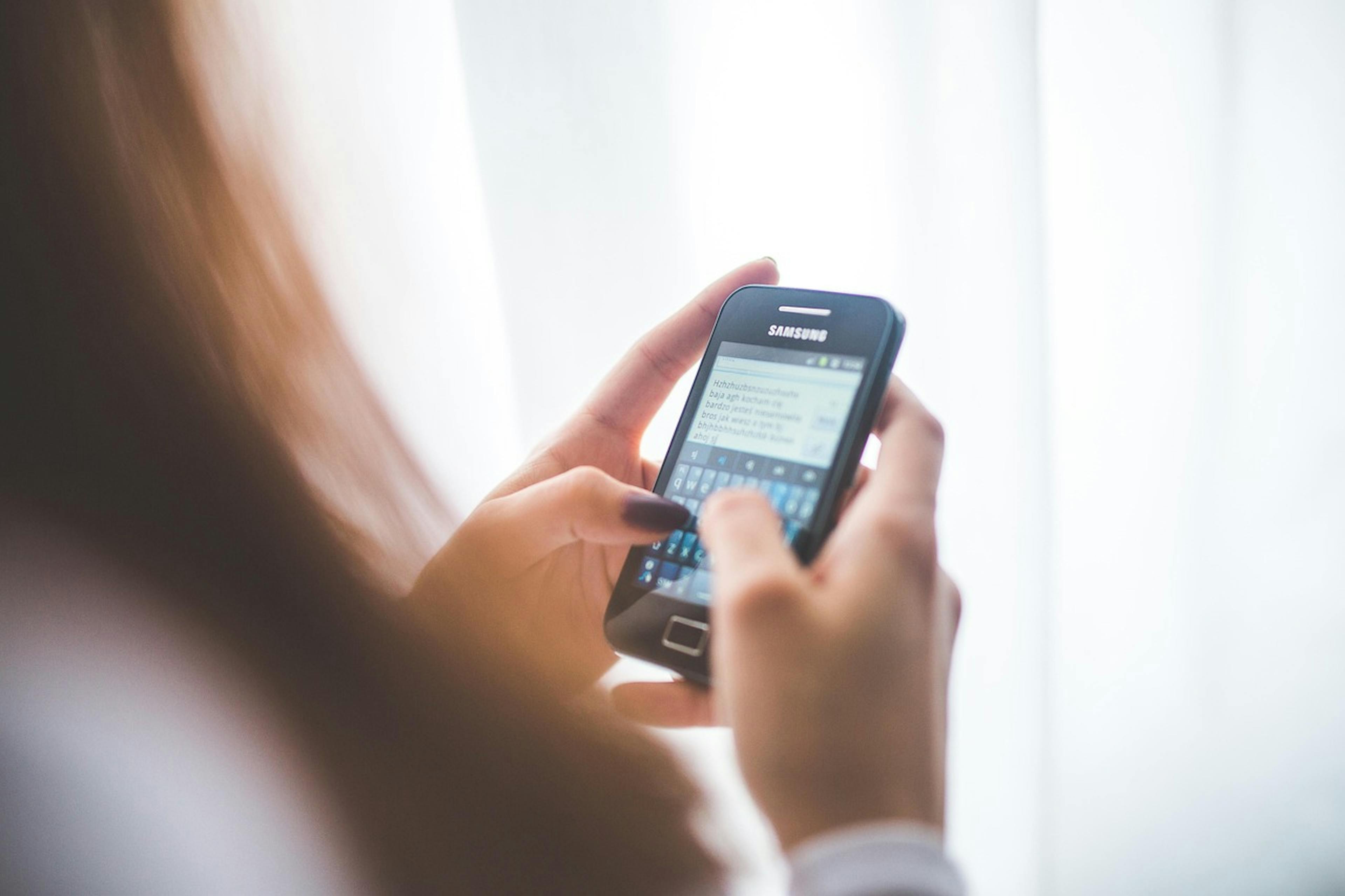 An image of a woman typing on her phone - it is the main image for the article "Journaling Apps: 7 Simple Journals That Make Journaling a Breeze"