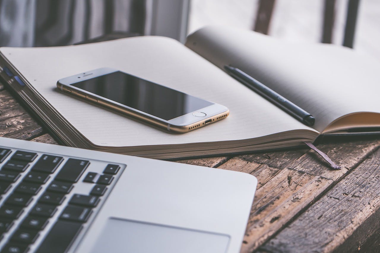 An image of a phone on top of a journal - it is an image for the article "Wellness Journal: Top 4 Journals That Improve Quality of Life"