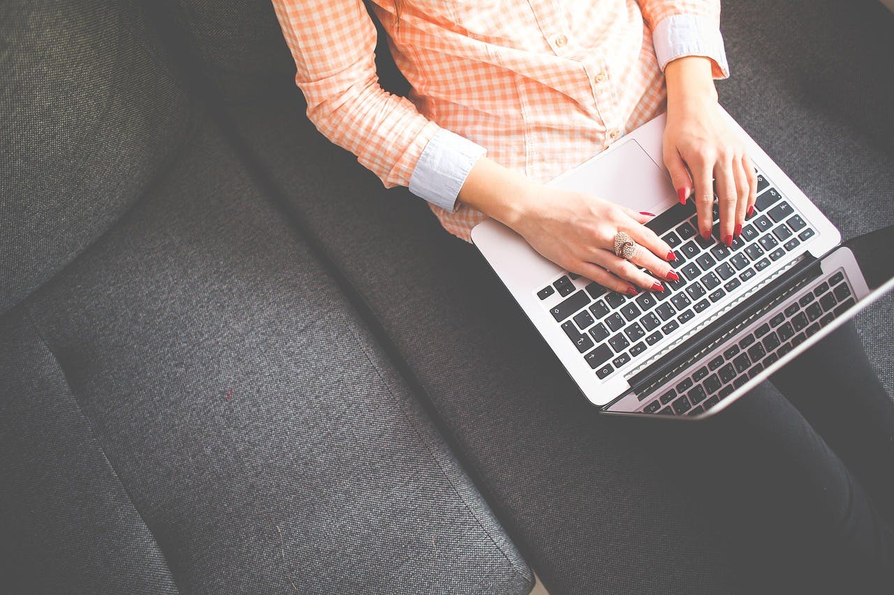 An image of a woman typing on a laptop - it is an image for the article "Mindfulness Journal: The Best 4 Journals That Actually Boost Awareness"