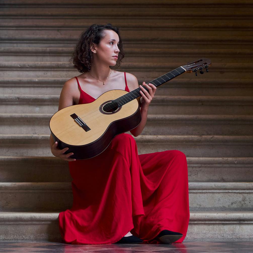 Roberta Gennuso holding a guitar in a red dress