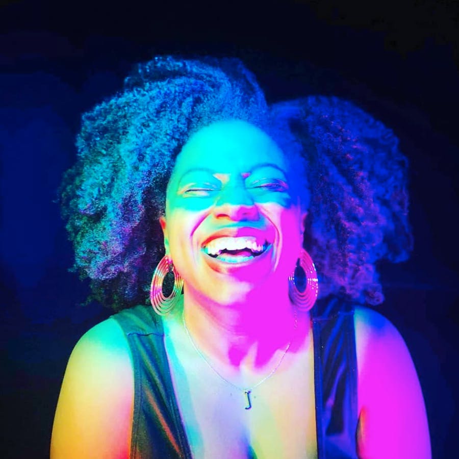 Profile photo of Jolie Dogget, laughing, with bold rainbow-colored lighting