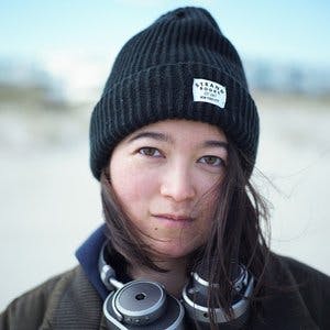 Profile photo of Erica Huang, wearing headphones around their neck and a black beanie hat