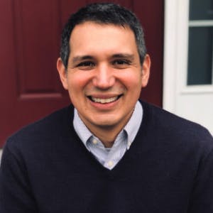 Profile photo of Matthew Potts, wearing a navy blue sweater and a light-blue collared shirt