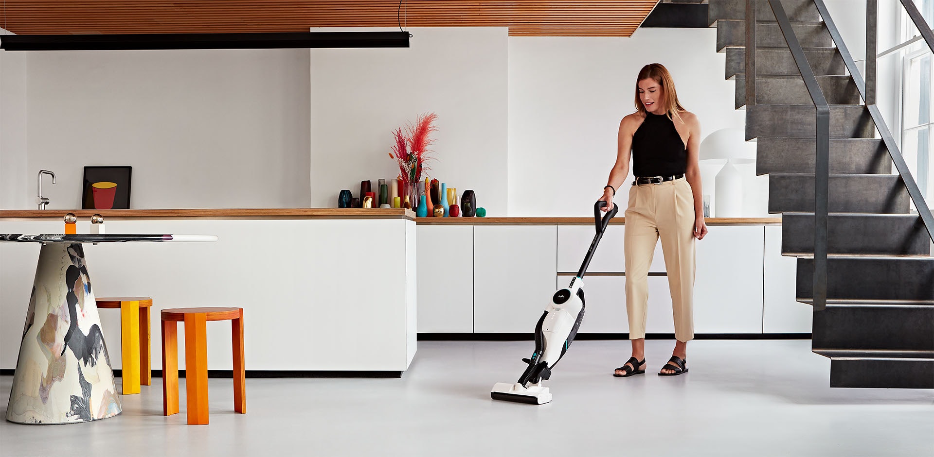A woman using a Pure Cordless vaccum cleaner from Lupe Technology