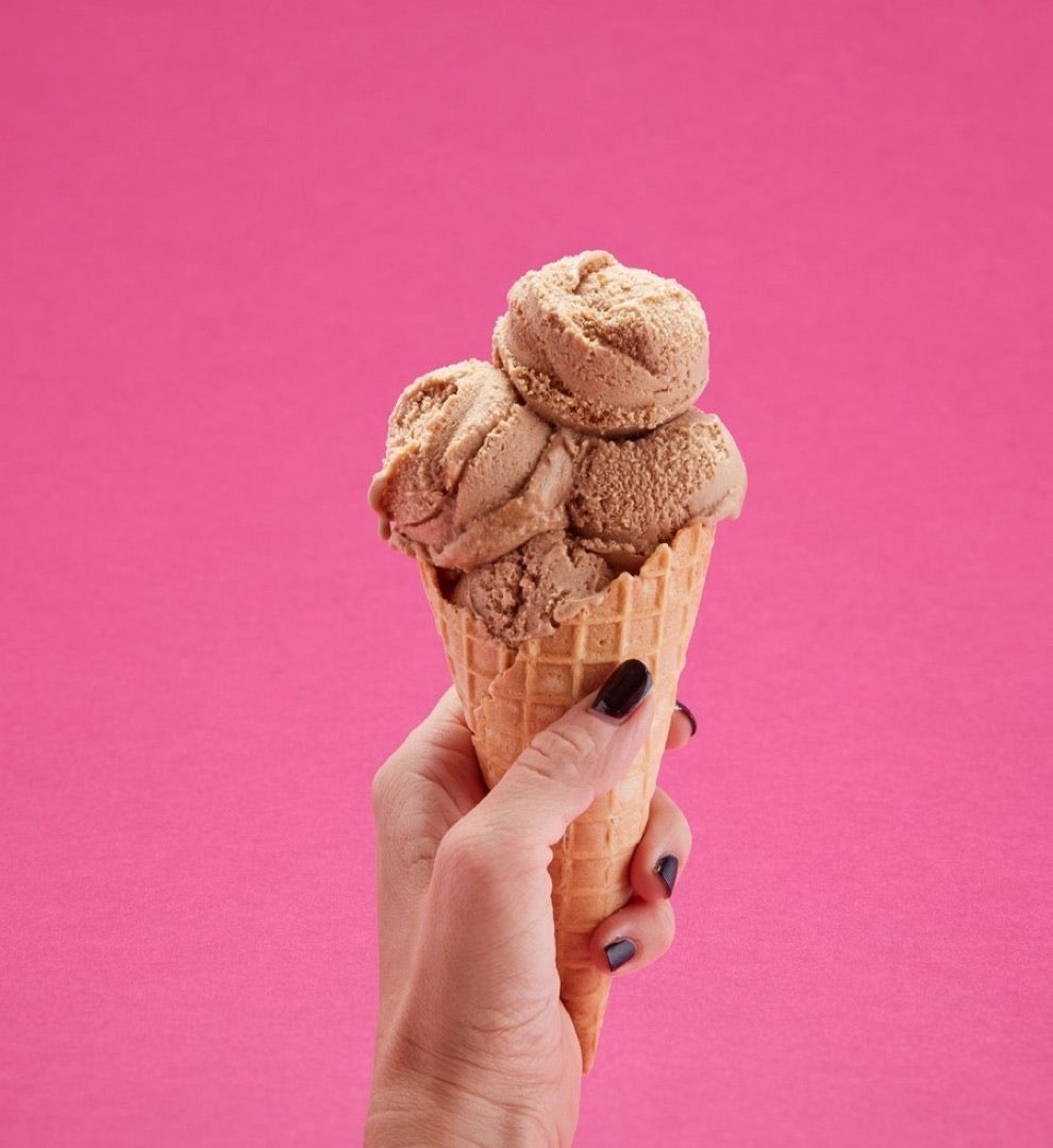 Image of a female hand holding a waffle cone with chocolate coconut ice-cream.