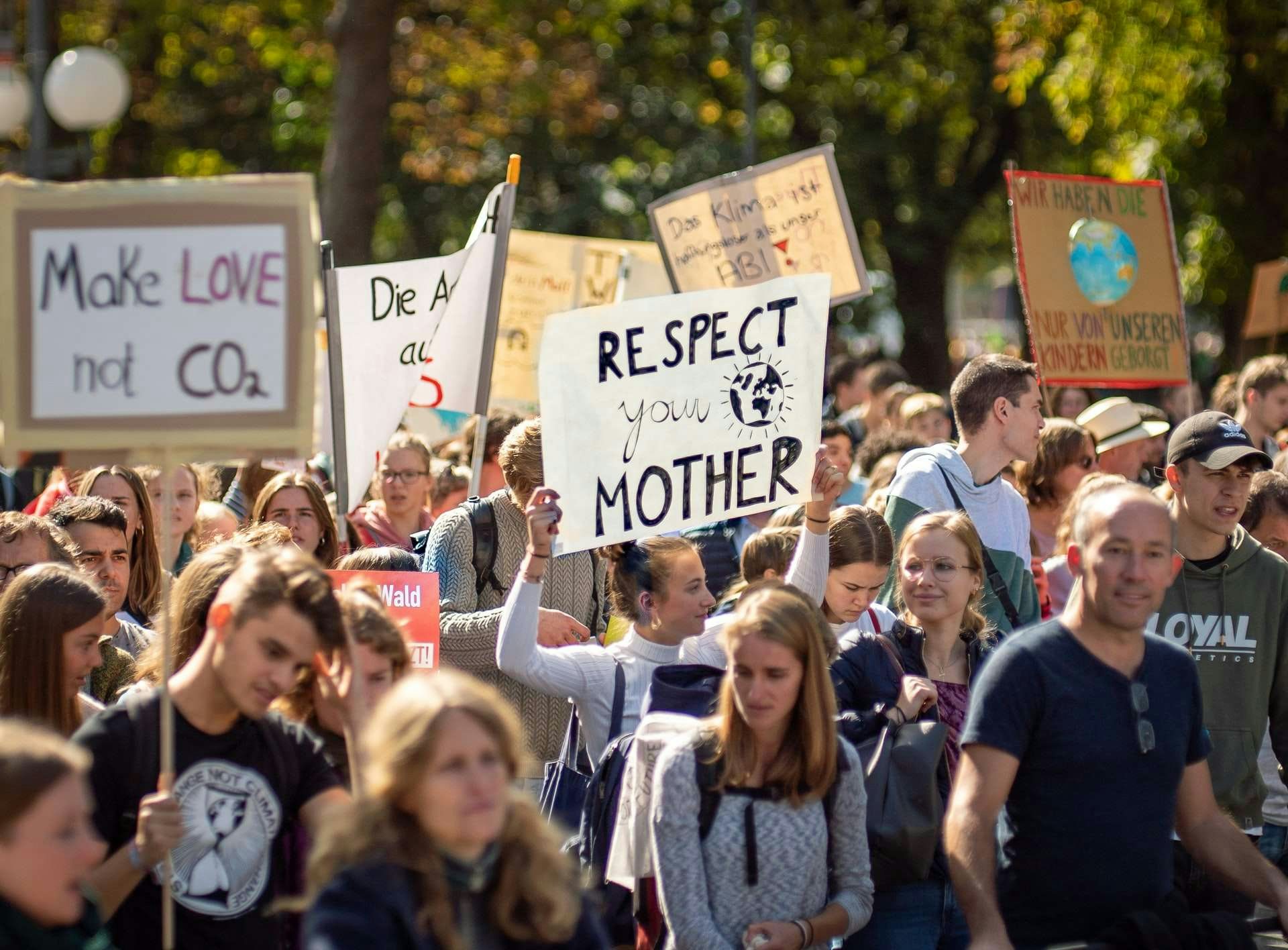 Crowd holding banners which say 'make love not CO2' and 'respect your mother earth'