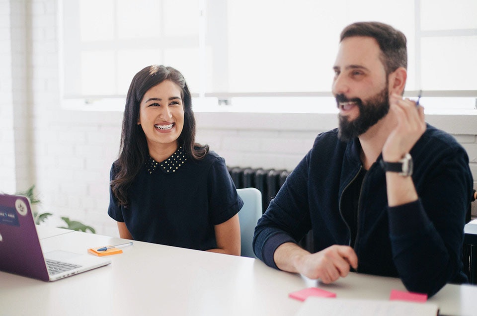 Two people laughing at a desk in an office environment