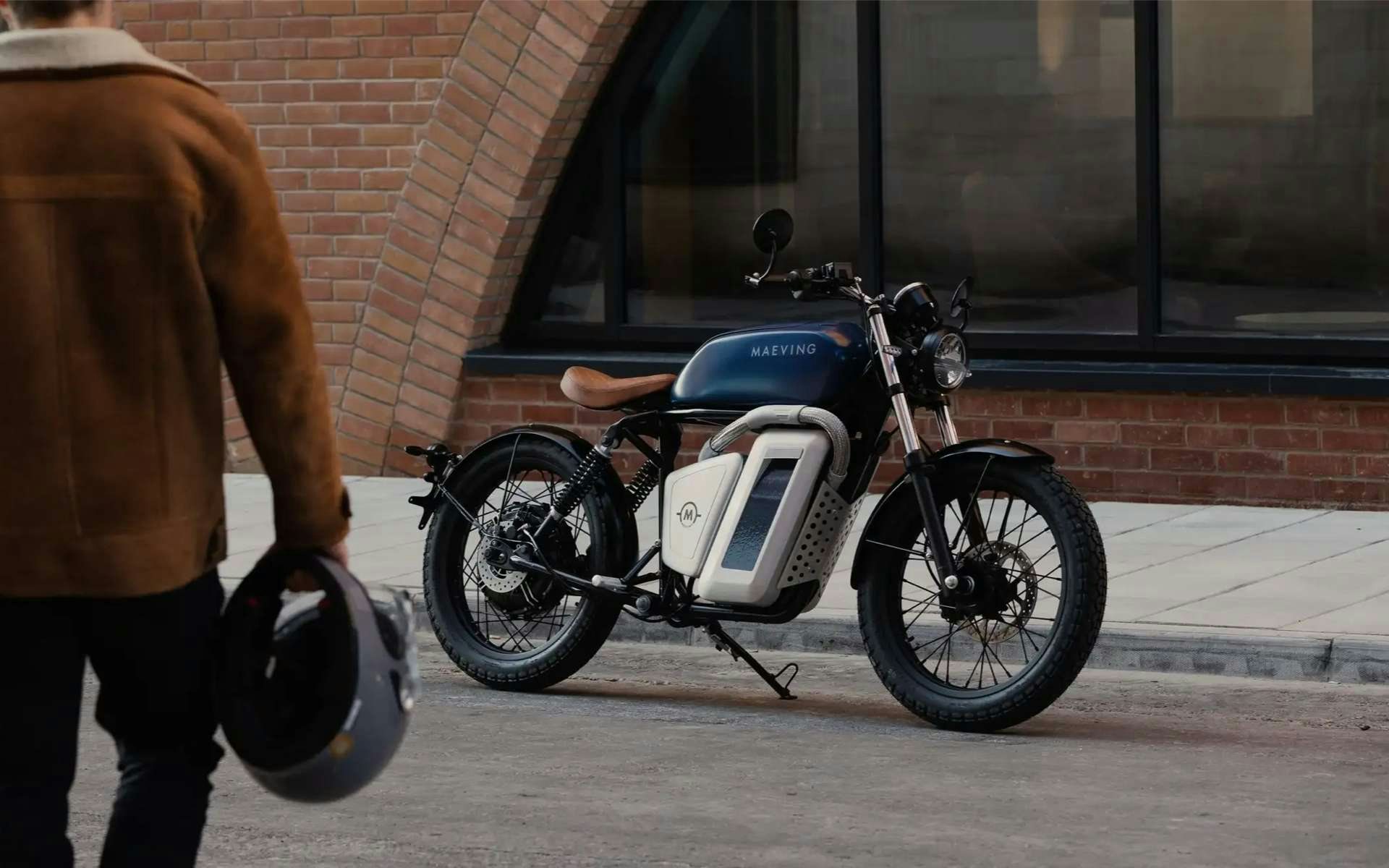 Man carrying helmet walking towards a Maeving electric motorbike