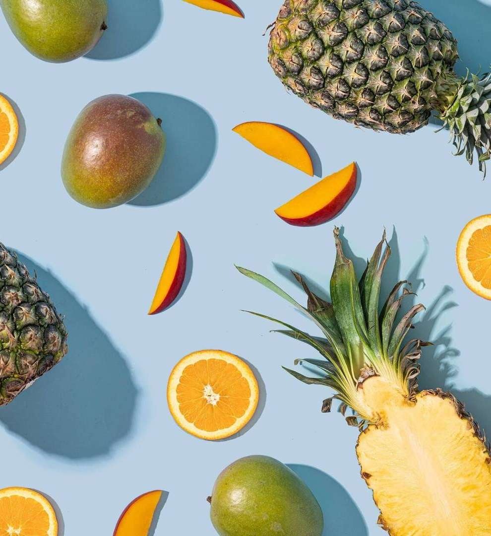Overhead image of pineapples, oranges and papaya fruit.