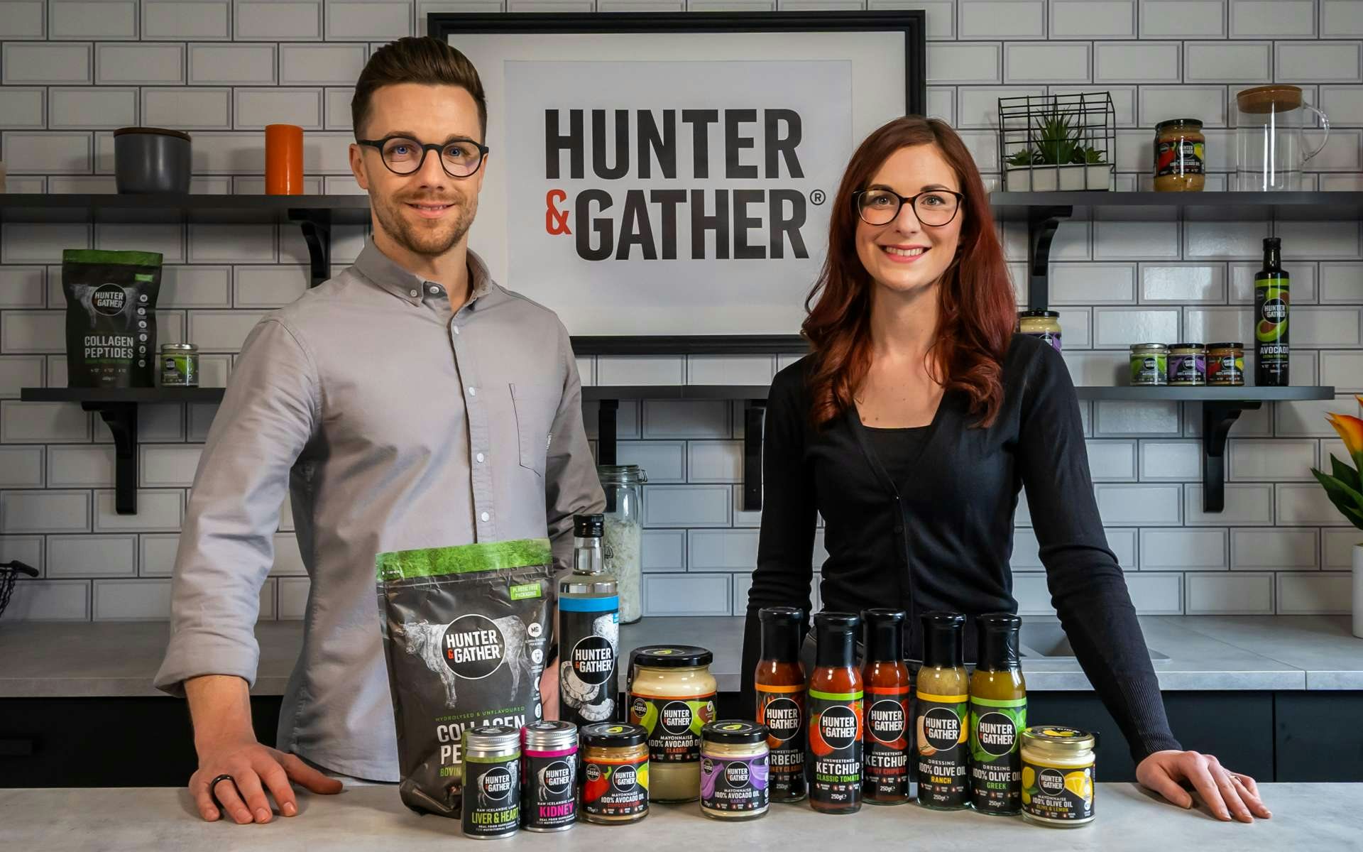 Jeff and Amy, the founders of Hunter and Gather with a range of healthy food products in front of them. 