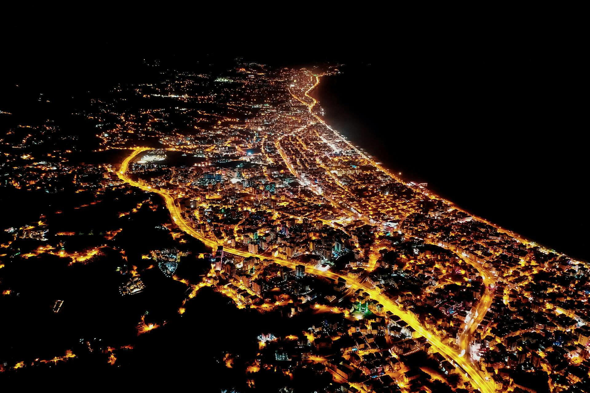 lit up coastal city at night seen from above