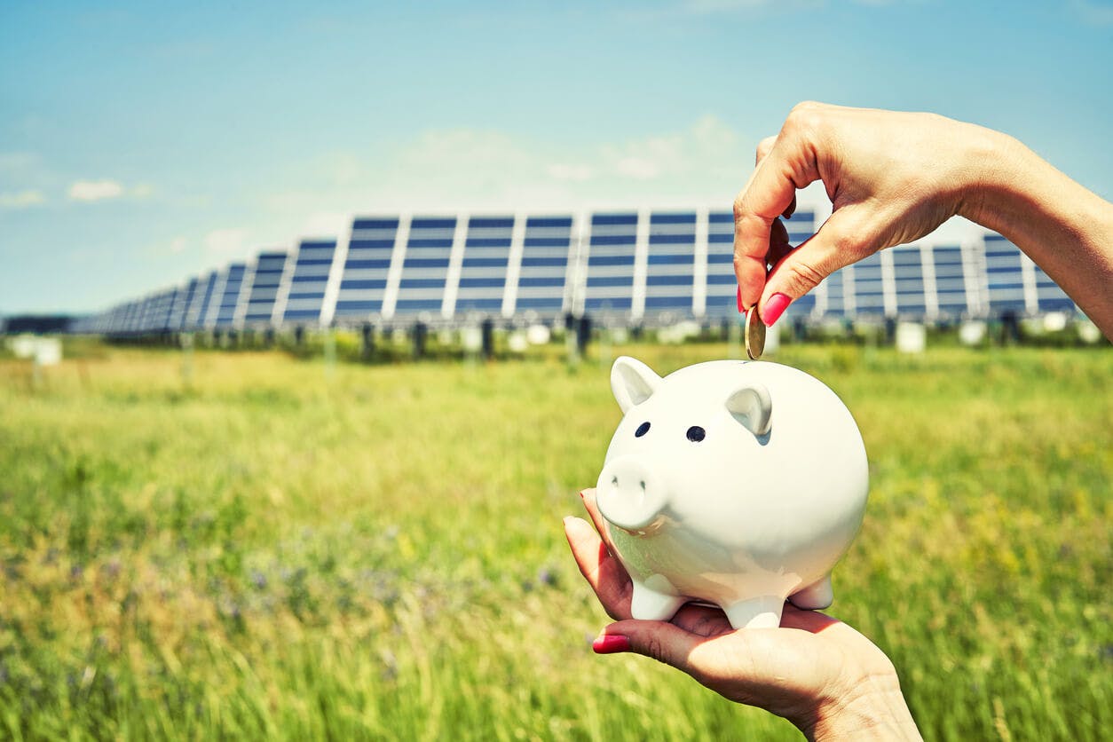 Cofrinho simbolizando investimento em frente as placadas solares.