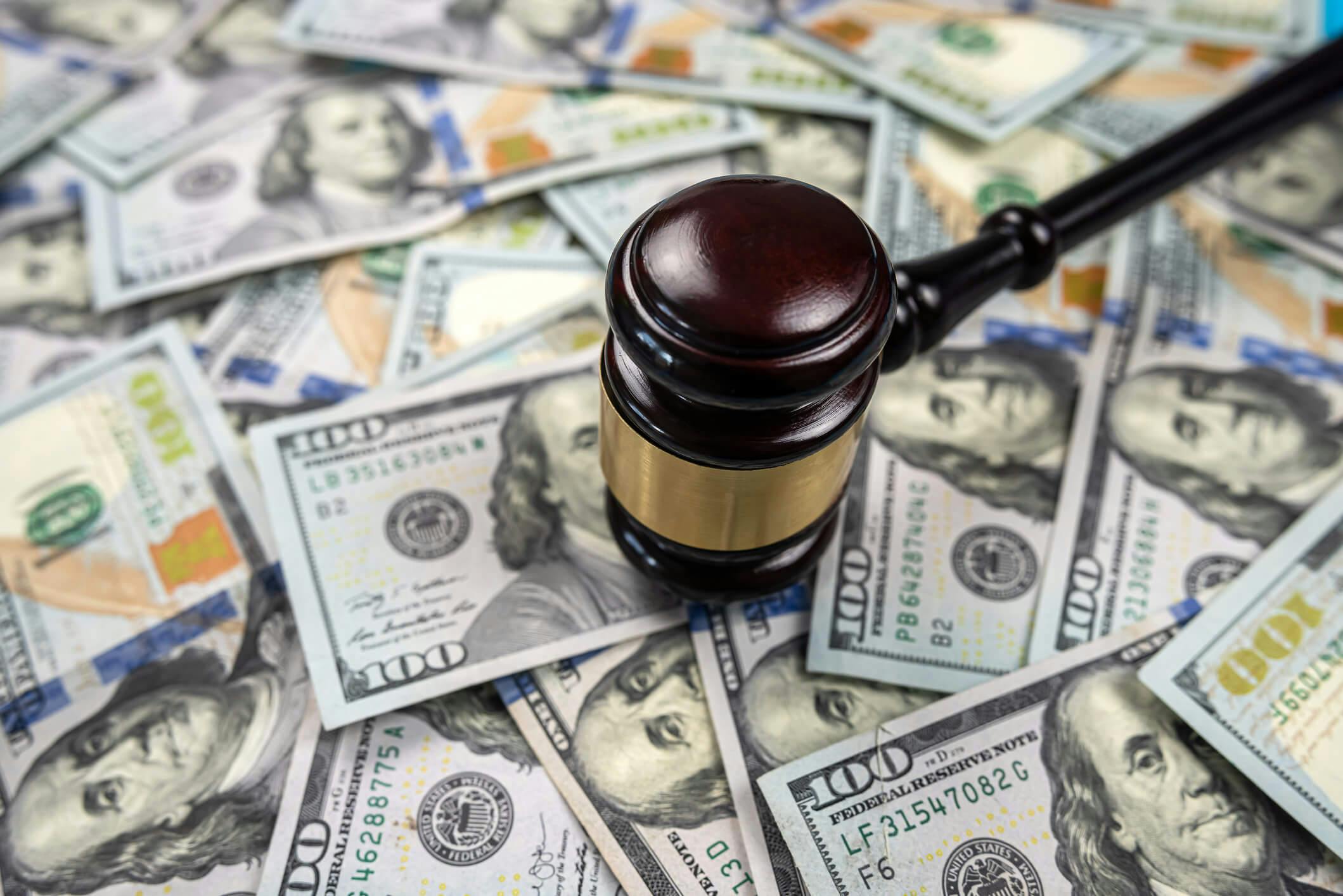 Martelo de madeira forte está em notas de dólar dispersas isolado