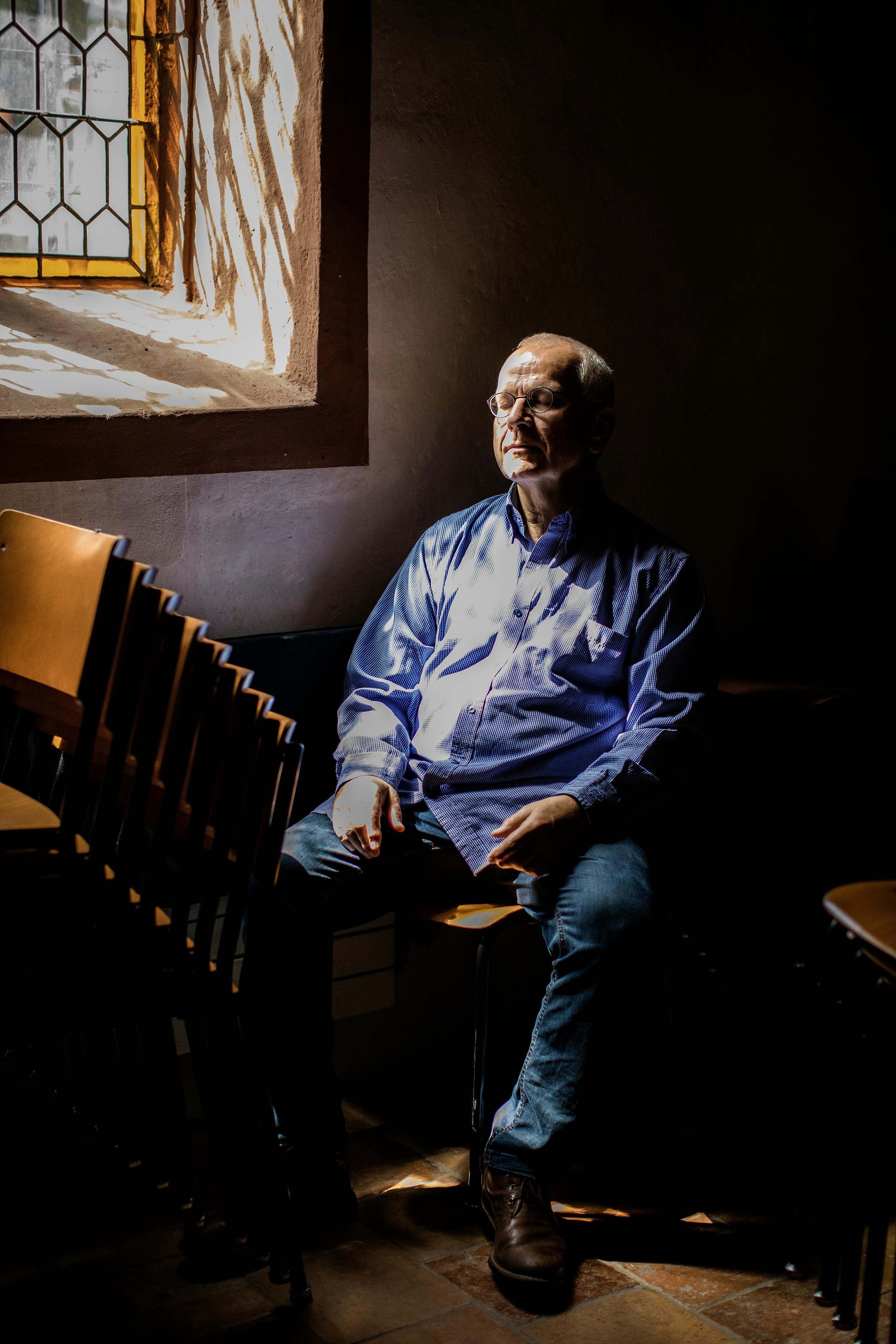 Duerr sitting in a dimly lit church, with sunlight streaming through a window.