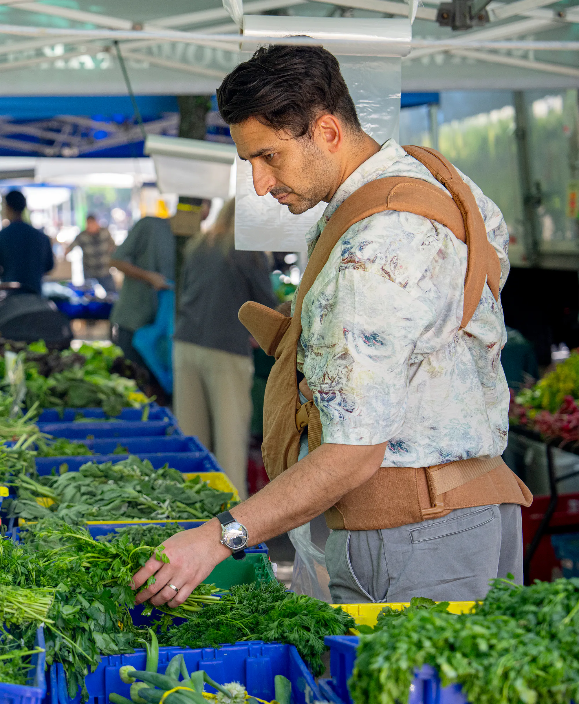 Junger Vater mit Baby in der Trage auf einem New Yorker Bauernmarkt.