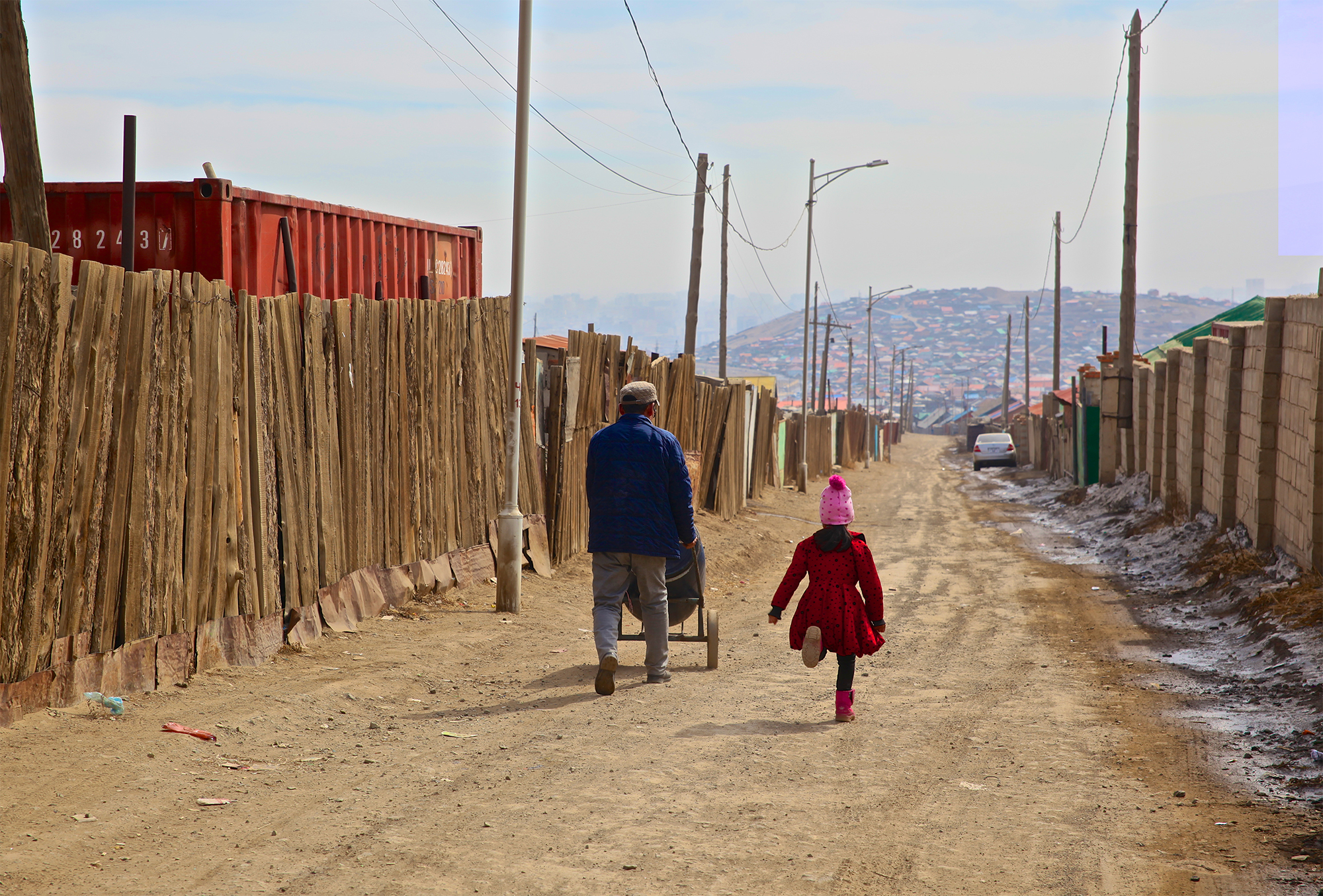 Mann und Kind gehen eine Straße entlang in Richtung Ulaanbaatar.