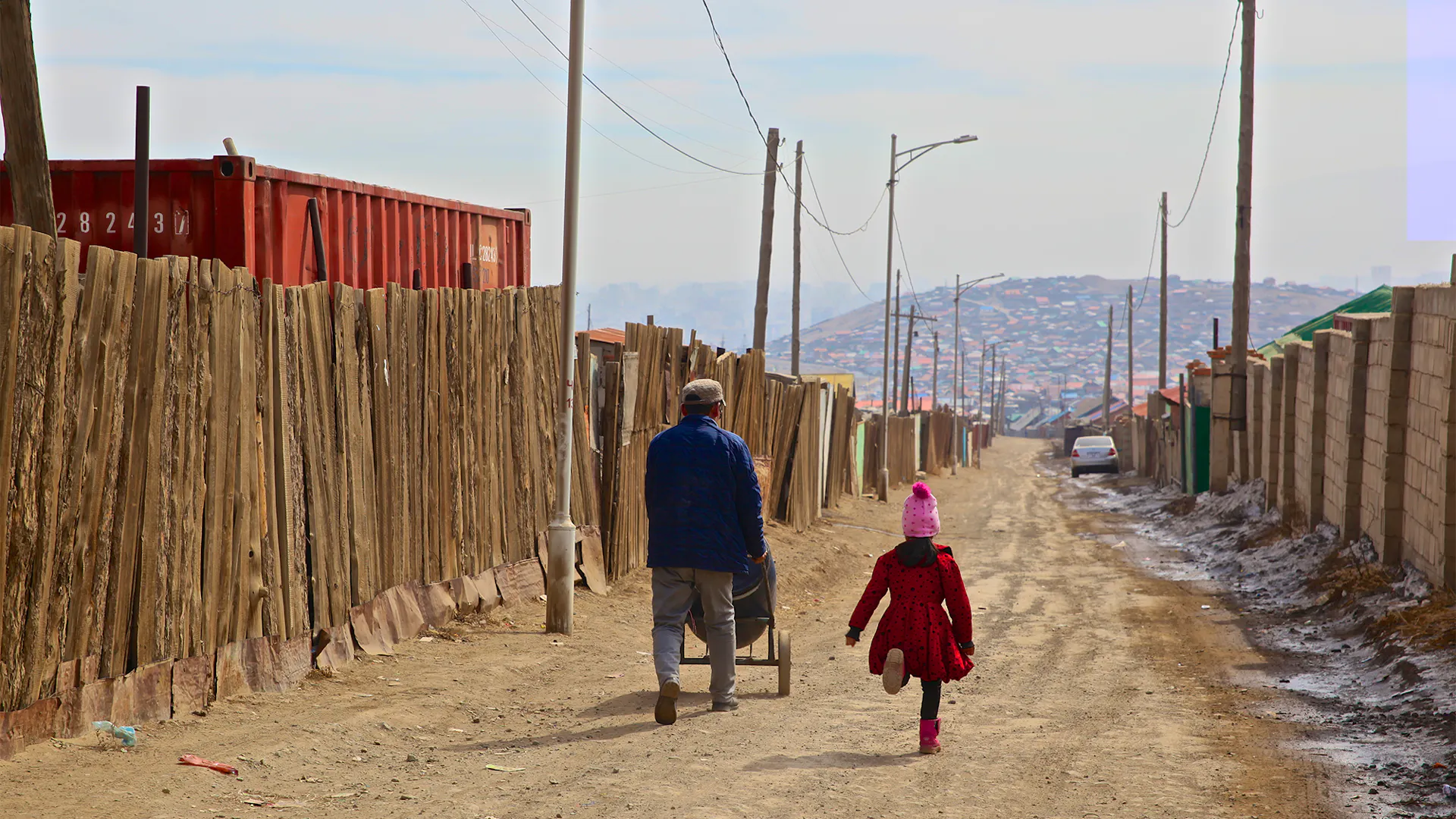 Mann und Kind gehen eine Straße entlang in Richtung Ulaanbaatar.