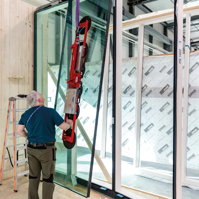 Assembly of the window elements in the carpentry workshop of Erne AG. In each installation step, six of the roughly four-meter-high windows and frames were placed en bloc to form the outer shell.