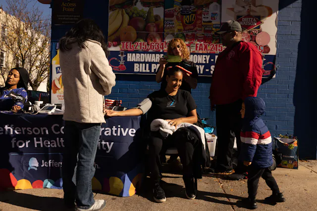 Maggie Perez (standing, center), a Jefferson health educator, meets members of the community in Philadelphia. As part of the Closing the Gap initiative, dedicated clinical personnel, community health workers and health educators like Maggie provide health services outside corner stores and at other locations in Philadelphia. They also help with resources such as food, health education or housing, and connect people to trusted sources of care.