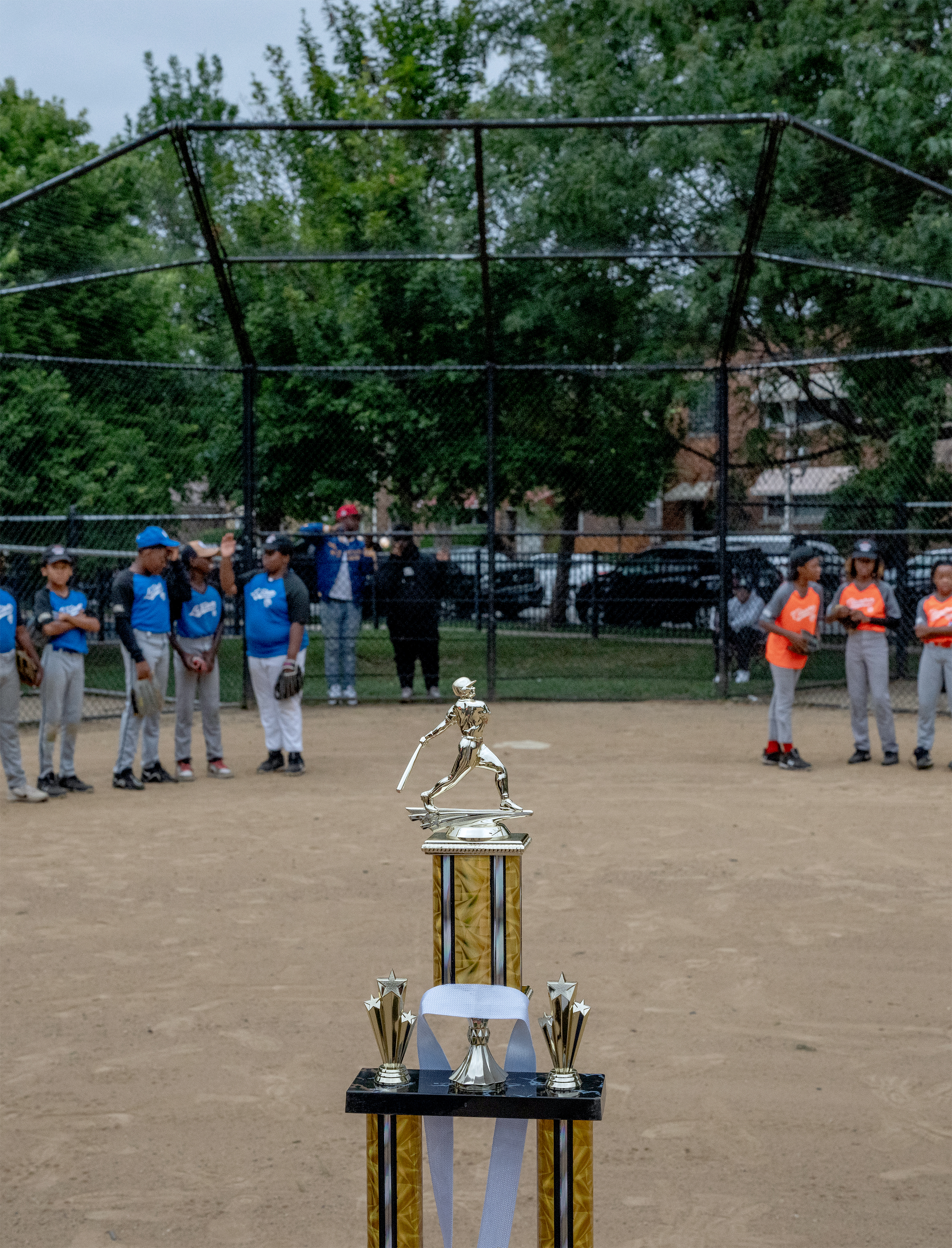 Baseball Cup standing in front of two youth baseball teams.