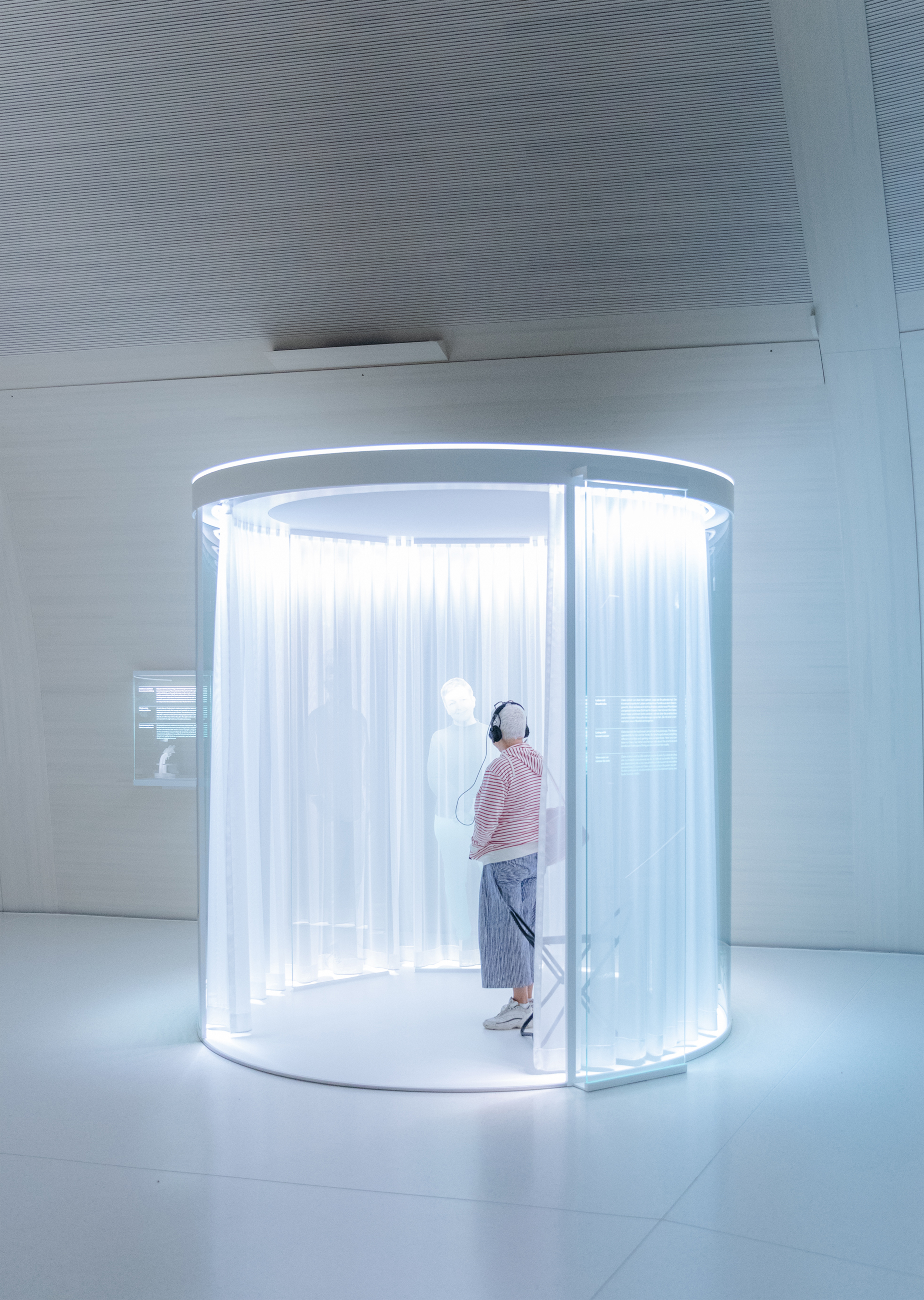 Frau betrachtet eine holografische Person auf einer Ausstellung im Novartis Pavillon in Basel.