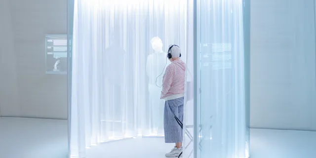 Frau betrachtet eine holografische Person auf einer Ausstellung im Novartis Pavillon in Basel.