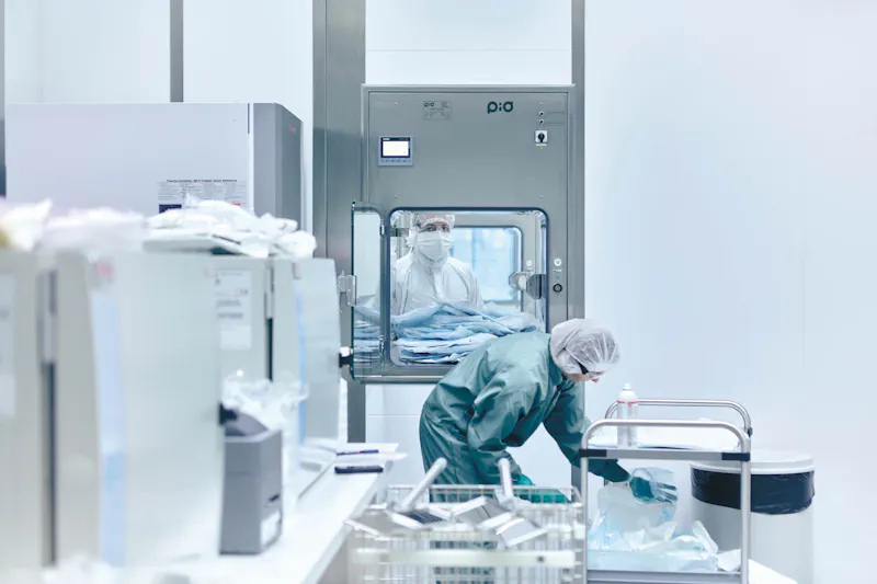 Eine Mitarbeitende der Zell- und Genproduktion in Stein bereitet im Schutzanzug Material für die Produktionszone vor.