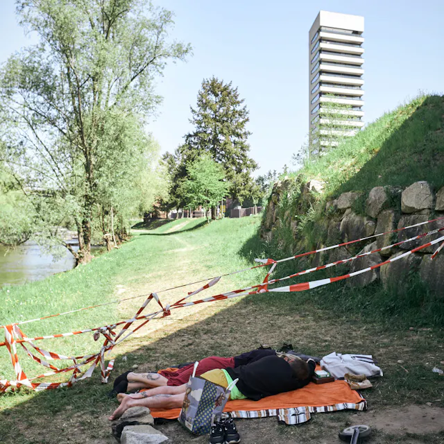 Ein Pärchen schläft auf einer Picknick-Decke neben dem Grenzzaun.