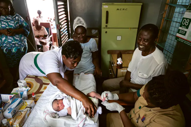 Nurses take a blood sample from a baby to test it for sickle cell disease.