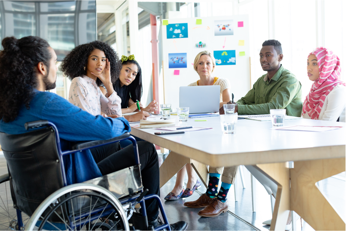A group of people sit around a work table for a meeting. 