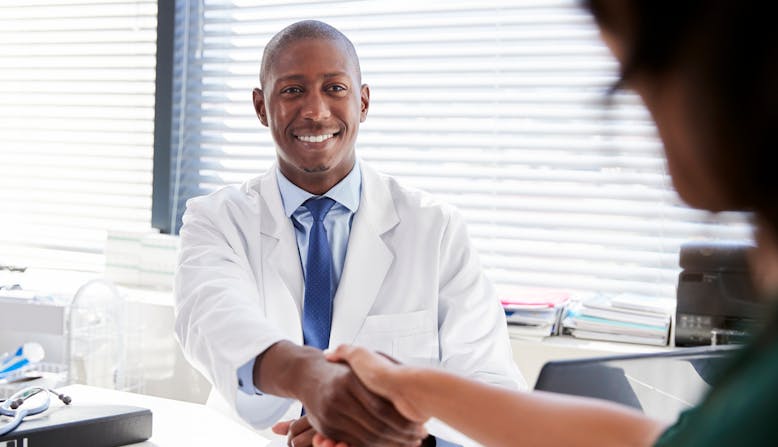A doctor shakes hands in an office.