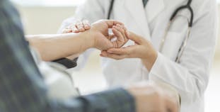 A doctor inspects a patient's hand.